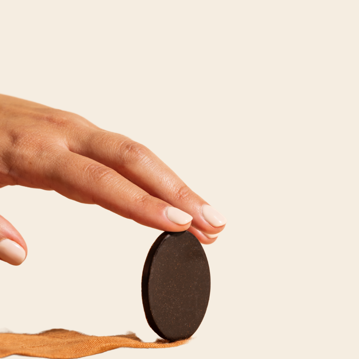 A woman's hand balancing Compound's cocoa-free chocolate medallion on one hand