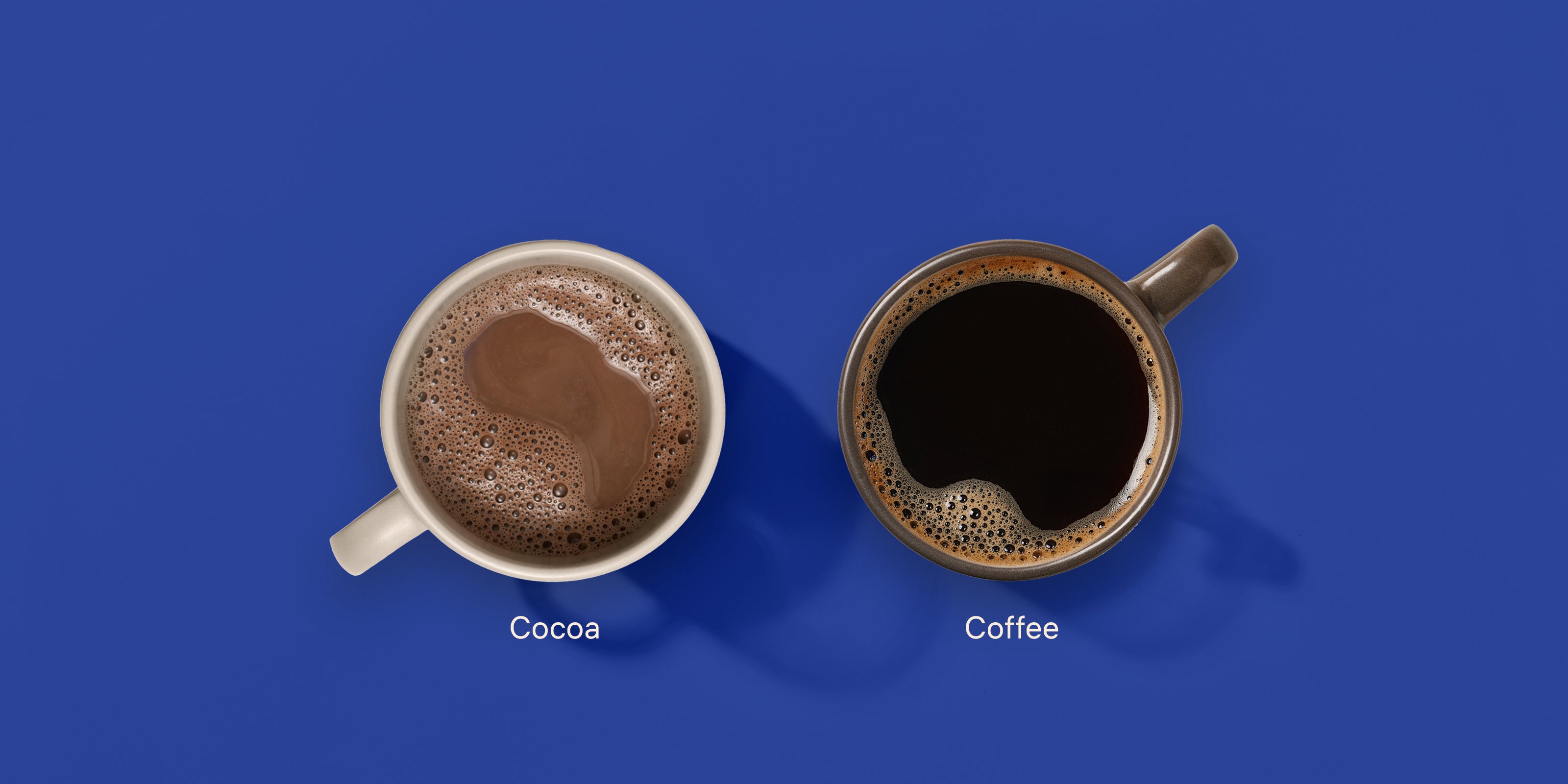 Two mugs on a blue background. One filled with hot cocoa and another one with black coffee. Image descriptions are cocoa and coffee