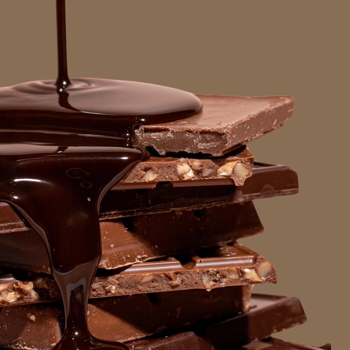 Stacked pieces of chocolate bark with melted dark chocolate being poured over them