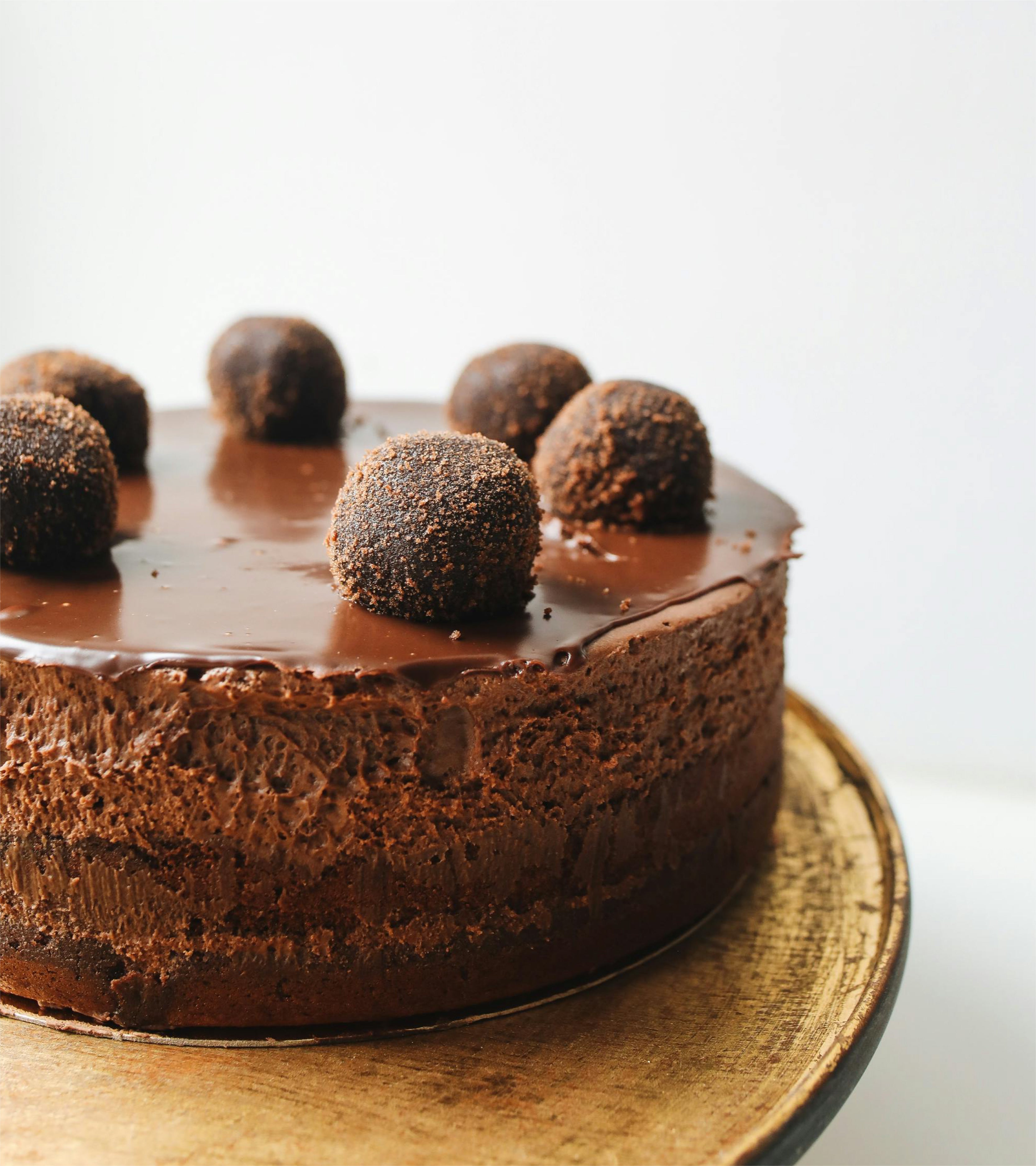 A dark chocolate layered cake with dark chocolate balls on top. Served on a gold plate